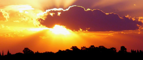 A bright orange sky, with the sun hiding behind a cloud