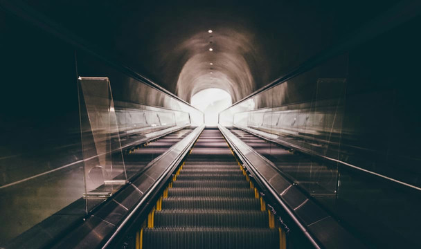 Looking up the stairs of an underground escalator leading up to the surface