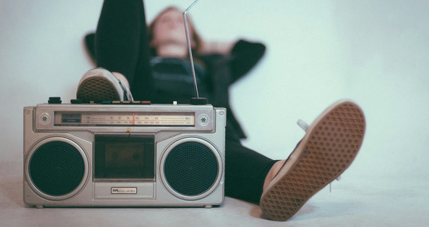 A person lying down, listening to an old radio