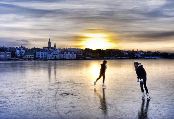 As the sun rises, two women skate across the frozen surface of Tjörnin, a pond in the centre of Reykjavík